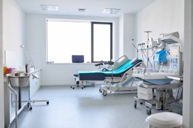 Parlak bir hastane odasında hasta yatakları, gelişmiş tıbbi gereçler ve lavabo bulunur. Bu alan gündüz saatlerinde hasta bakımı ve tıbbi faaliyetler için tasarlanmıştır..