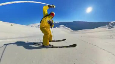 Deneyimli bir kayakçı, heyecan verici bir helezon kayağı macerası sırasında taze tozu oyar. Göz kamaştırıcı dağ manzarasının ve uzak bir dağ yamacındaki parlak güneşin tadını çıkarıyorum..