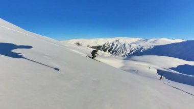 Tecrübeli bir kayakçı, serbest bir pist dışı macera sırasında derin toz karları oyarak, heyecan verici bir helikopter kayağı yapmaktan zevk alır. Temiz mavi gökyüzünün altındaki el değmemiş dağ manzarası...