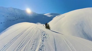 Helikopter kayağı macerası sırasında el değmemiş yamaçlardan inen deneyimli kayakçıların coşkulu özgürlüğüne tanık olun. Göz kamaştırıcı karlı dağlar ve berrak mavi gökyüzü mükemmel bir ortam yaratır.