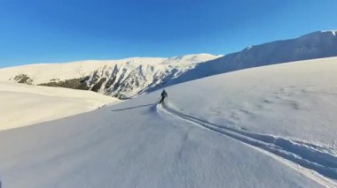 Deneyimli bir kayakçı aydınlık ve güneşli bir günde karla kaplı engin bir dağ yamacına heyecan verici izler kazır. Bu dinamik sarmal kayak macerası el değmemiş bir şekilde aşırı serbest hareketlilik sergiliyor.