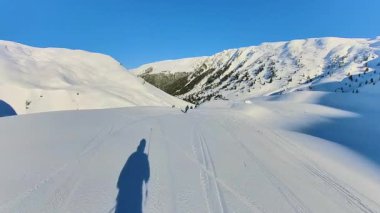 Uçsuz bucaksız bir dağ manzarasında, deneyimli bir kayakçının el değmemiş tozla iniş yapmasının heyecanını yaşayın. Parlak mavi gökyüzünün altında heyecan verici bir macera bekliyor..