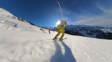 Yokuş aşağı kaymanın neşesini dinamik birinci şahıs bakış açısıyla yaşayın. Mükemmel bir kış gününde açık mavi gökyüzünün altındaki karlı dağ manzarasının tadını çıkar..