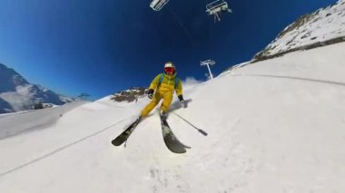 Bir kayakçının temiz mavi gökyüzü altında dinamik bir birinci şahıs perspektifiyle yakalanan görkemli dağdaki el değmemiş karları oyduğu bir kış sporu macerasının neşesini yaşayın..