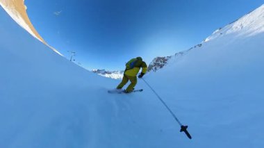 Parlak mavi bir gökyüzünün altında el değmemiş, karla kaplı dağ yamaçlarında kaymanın heyecan verici heyecanını yaşayın. Bu birinci şahıs perspektifi dinamik hareketi ve nefes kesici dağları yakalar.