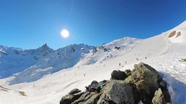 Parlak, açık mavi gökyüzünün altındaki kar kaplı Alpler 'in nefes kesici panoramik manzarasının tadını çıkar. Kayakçılar ve snowboardcular el değmemiş beyaz yamaçlarda güneşli kış günlerinin tadını çıkarıyorlar.