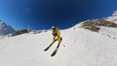 Karlı bir dağ macerasının heyecanını yaşayın bir kayakçının dinamiği oyması güzel, açık bir günde el değmemiş bir yamacı geri çevirir. Arka planda diğer kayakçılar ve kayak asansörleri görünür