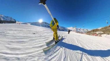Parlak bir kış gününde yokuş aşağı kaymanın neşesini birinci şahıs perspektiften yaşayın. Temiz havanın, taze karın ve berrak mavi gökyüzünün altında büyüleyici dağ manzarasının tadını çıkar..