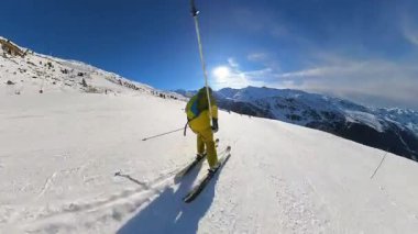 Canlı, mavi bir gökyüzünün altındaki görkemli karla kaplı dağlarda el değmemiş, güneşli bir dağda kayak yapmanın coşkulu özgürlüğünü hisset. Dinamik bir kış sporları macerası.