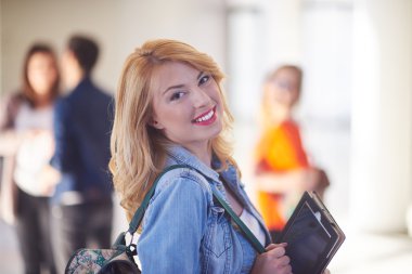 Modern okul üniversitesinde kapalı alanda tablet bilgisayarda çalışan mutlu öğrenci kız.