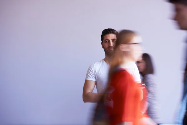 Étudiant travaillant sur tablette, groupe de personnes passant par — Photo