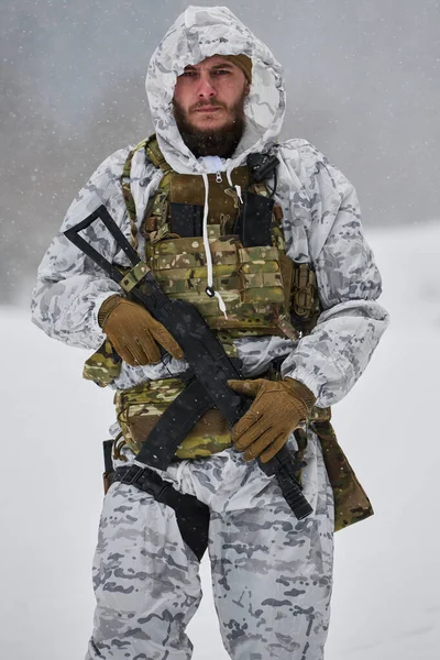 Beyaz kar kamuflajı ve taktik yelek giyen bir asker, kar yağan bir havada tüfeğini tutuyor, hazır olma, dayanıklılık ve soğuk hava askeri operasyonlarını karlı bir havada sürdürüyor..