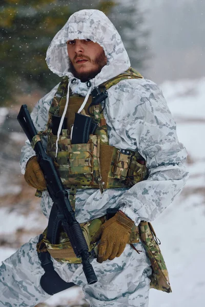 Beyaz kış kamuflajı ve taktik yelek giyen bir erkek asker, karlı bir ormanda durup hazırlık, hayatta kalma, soğuk hava operasyonları ve kışın askeri devriye görevleri yaparken tüfeğini tutuyor.