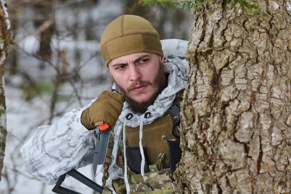 Kış kamuflajlı sakallı bir asker, karlı bir ormandaki bir ağacın arkasına saklanır. Taktik bir bıçağı kavrar ve radyo dinler. Gerginlik, gizlilik, hayatta kalma ve askeriyenin hazırlığını iletir..