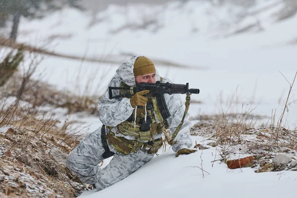 Kış eğitimli asker beyaz kamuflaj ve taktik teçhizatla karlı bir arazide elinde tüfekle sürünüyor, soğuk hava askeri eğitimi sırasında manevra, gizlilik ve hazırlık eğitimi yapıyor.