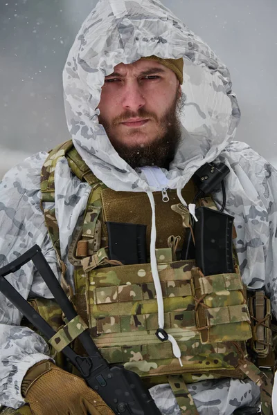 Kar maskesi ve taktik yelek giymiş, karlı bir arazide tüfek tutan bir askerin yakın plan portresi. Stoik ifade soğuk hava operasyonları sırasında odak, esneklik ve hazırlık iletir.