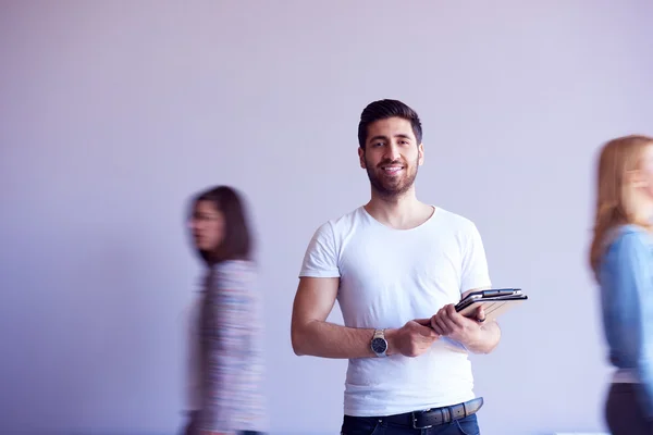 Étudiant travaillant sur tablette, groupe de personnes passant par — Photo