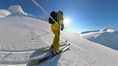 An exhilarating point-of-view shot captures a skier enjoying an epic heliskiing and freeride adventure. Experience the thrill of carving through fresh, deep powder snow down a majestic mountain under