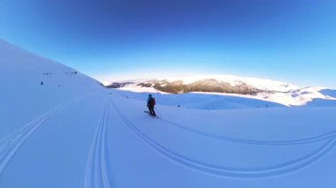 Taşrada kayak yapmanın, açık mavi bir gökyüzü altında kar altında gezmenin tadını çıkar. Saf bir kış dağ manzarasının dingin güzelliğini ve özgürlüğünü tecrübe edin..