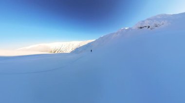 Maceraperest bir kayakçı, muhteşem bir dağdan kayak yaparak taze, derin kar parçalarını oyma özgürlüğünün tadını çıkarır. Bu heyecan verici serbest dolaşım, nefes kesici manzaralar sunuyor.
