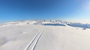 Kıdemli arkadaşlar, helikopter pistinin coşkulu dünyasını kucaklıyor, derin toz karda taze izler oyuyor. Parlak mavi gökyüzünün altındaki el değmemiş karlı dağlarda nefes kesici bir serbest gezinti.