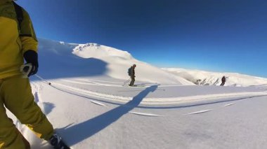 Dostlar, el değmemiş, el değmemiş, güneşin ıslattığı bir dağ manzarasında, el değmemiş, derin toz kar içinde, heyecan verici bir helezon kayağı ve serbest gezisi için toplanırlar..