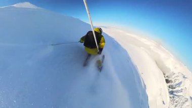 Experience the thrill of off-piste heliskiing in deep powder snow from a unique point of view. Enjoy a breathtaking descent down a vast, snow-covered mountain on a sunny day.