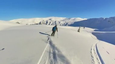 Maceracı bir kıdemli kayakçı, temiz kış gününün ve muhteşem manzaranın tadını çıkararak, el değmemiş dağlarda nefes kesen bir pistte kayak turu yapıyor..