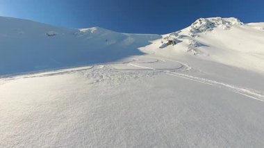 Yaşlı arkadaşlar, el değmemiş pist dışı arazide gezinerek heyecan verici bir helikopter ve serbest gezintiye çıkıyorlar. Açık mavi gökyüzünün altında taze, derin kar yağışının heyecanını yaşarlar.
