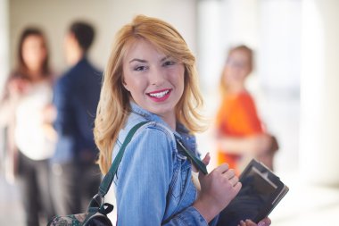 Modern okul üniversitesinde kapalı alanda tablet bilgisayarda çalışan mutlu öğrenci kız.