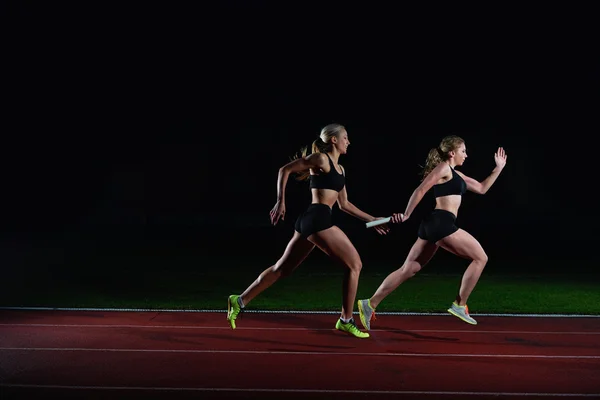 Athletic runners passing baton in relay race — Stock Photo, Image