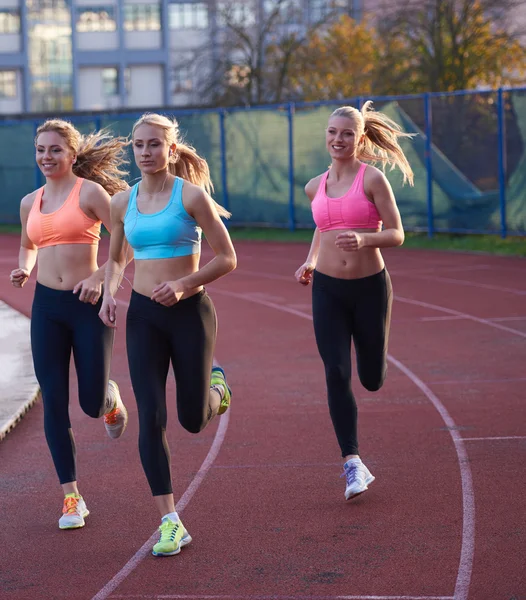 Groupe d'athlètes féminines en course sur piste de course d'athlétisme — Photo