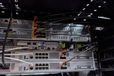 Bir veri merkezi sunucu odasındaki rafa monte edilmiş sunucuların, anahtarların ve ağ kablolarının kapanışı, bilişim altyapısı, bağlantı ve şirket ağ donanım ve bakım işlerini gösteriyor.