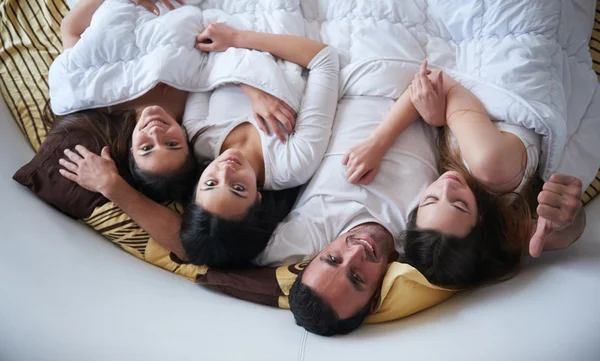 3 人の美しい女性が付いているベッドでハンサムな男 — ストック写真