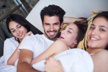 üç güzel kadınlarla yatakta yakışıklı adam