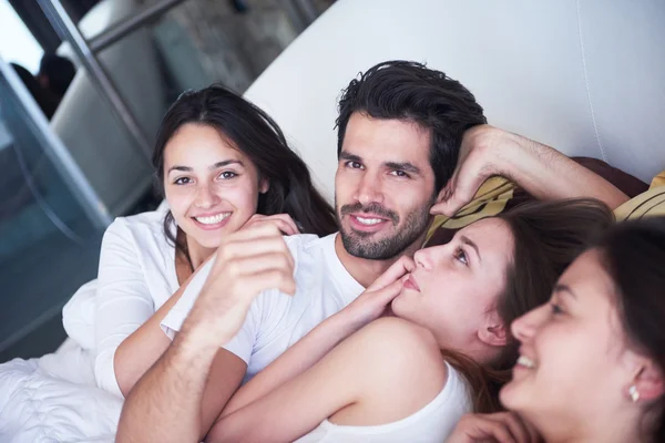 Homem bonito na cama com três mulheres bonitas — Fotografia de Stock