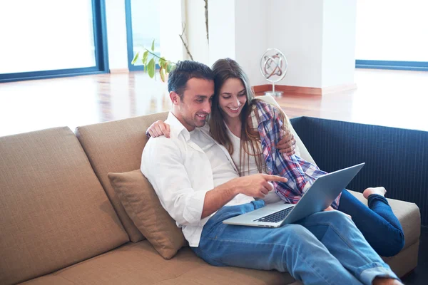 Relaxado jovem casal trabalhando no computador portátil em casa — Fotografia de Stock