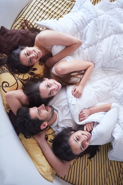 Homem bonito na cama com três mulheres bonitas — Fotografia de Stock