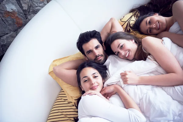 Homem bonito na cama com três mulheres bonitas — Fotografia de Stock