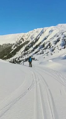 El değmemiş, karla kaplı dağlarda helikopter kayağı yapmanın neşesini yaşayın. Uçsuz bucaksız kış aylarında unutulmaz bir serbest macera sergileyen bir kayakçı, bekleyen bir helikoptere doğru iniyor.