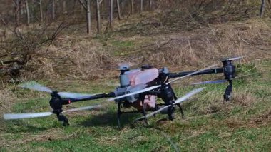 Modern bir tarımsal dron, meyve ağacı bahçesinin üzerine otomatik ekin koruma sisi püskürtmeye hazırlanıyor. Bu akıllı tarım teknolojisini ve hassas tarımı vurguluyor