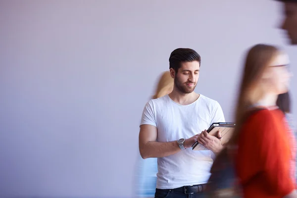 Studentin arbeitet an Tablet, Menschengruppe kommt vorbei — Stockfoto