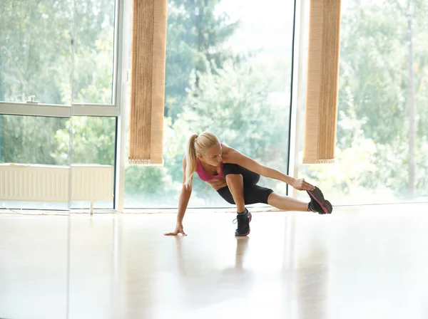 Mujer estirando y calentando para su entrenamiento en un gimnasio —  Fotos de Stock