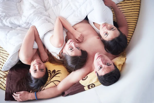 Homem bonito na cama com três mulheres bonitas — Fotografia de Stock