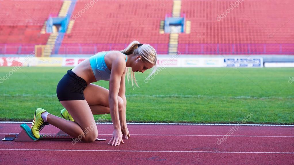 Side view of female teen athlete in sports bra and tights successfully  finishing race on track at stadium Stock Photo