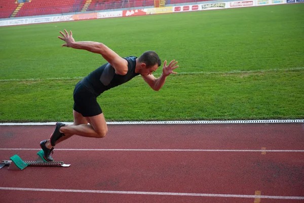 Atletisk mand starter på sporet - Stock-foto