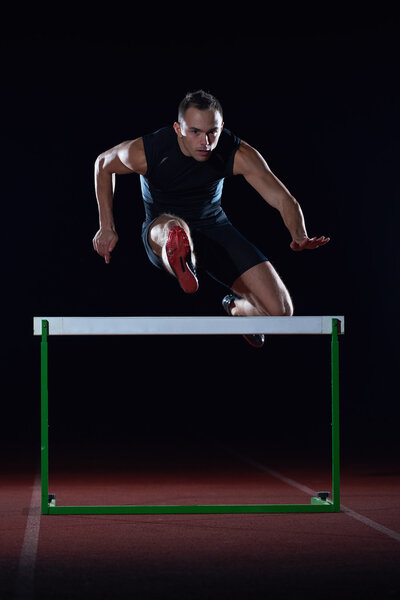 athlete jumping over a hurdles