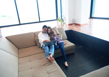 rahat genç bir çift evde dizüstü bilgisayar üzerinde çalışan