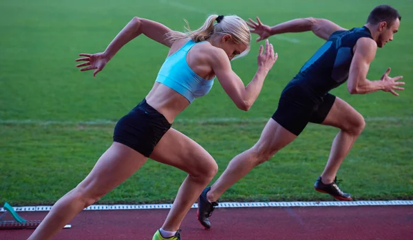 Woman running on athletics race track from start — Stock Photo, Image