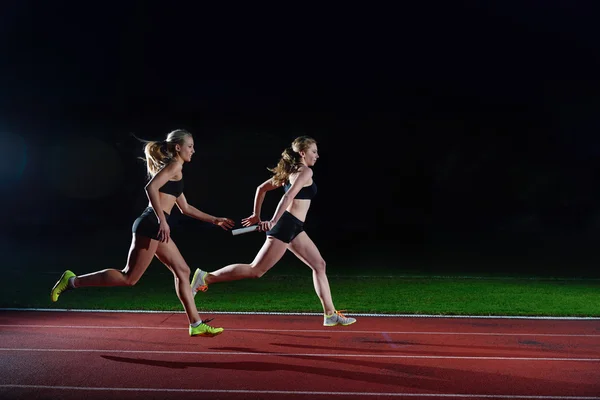 Atléticos corredores passando bastão na corrida de revezamento — Fotografia de Stock